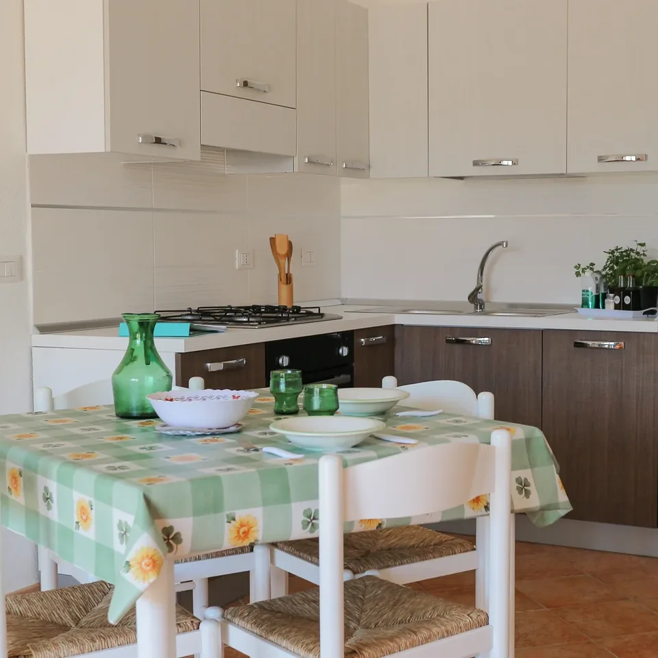 Cucina con pensili chiari e tavolo apparecchiato con tovaglia verde