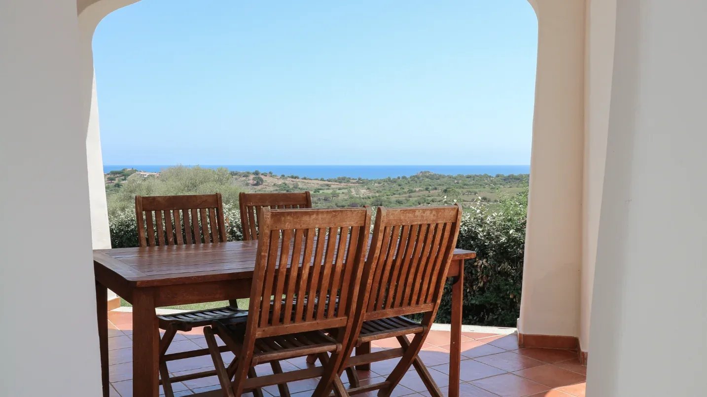 Tavolo in legno sotto un portico, con vista sulla campagna e sul mare in lontananza
